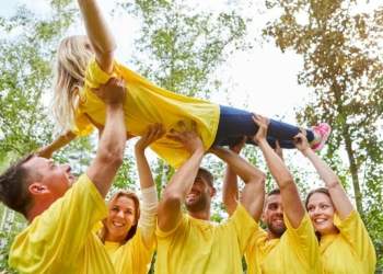 Team raises a woman together at a team building workshop