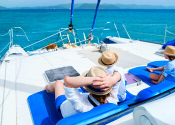 Back view of mother and her kids relaxing having great time sailing at luxury yacht or catamaran boat