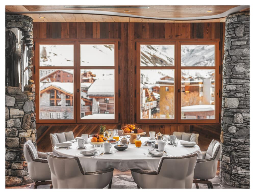 grande table ronde avec nappe blanche et fauteuils dressée avec des oranges pour le petit déjeuner