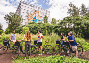 un groupe de personne à l'arrêt à vélos regardant un la fresque d'un bâtiment