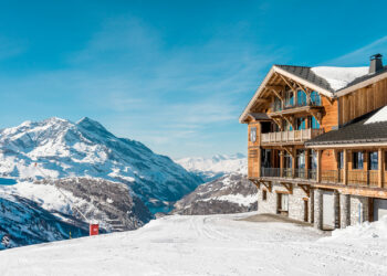 vue sur un chalet en bois dans les montagnes enneigées