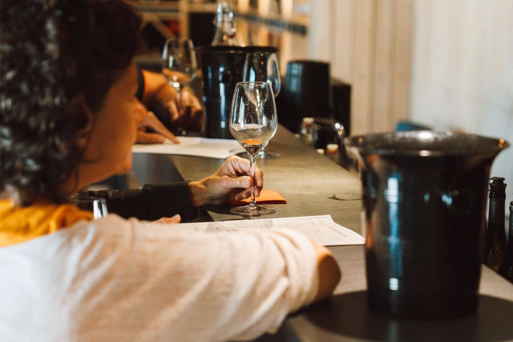 femme attablée au bar avec un verre de vin blanc