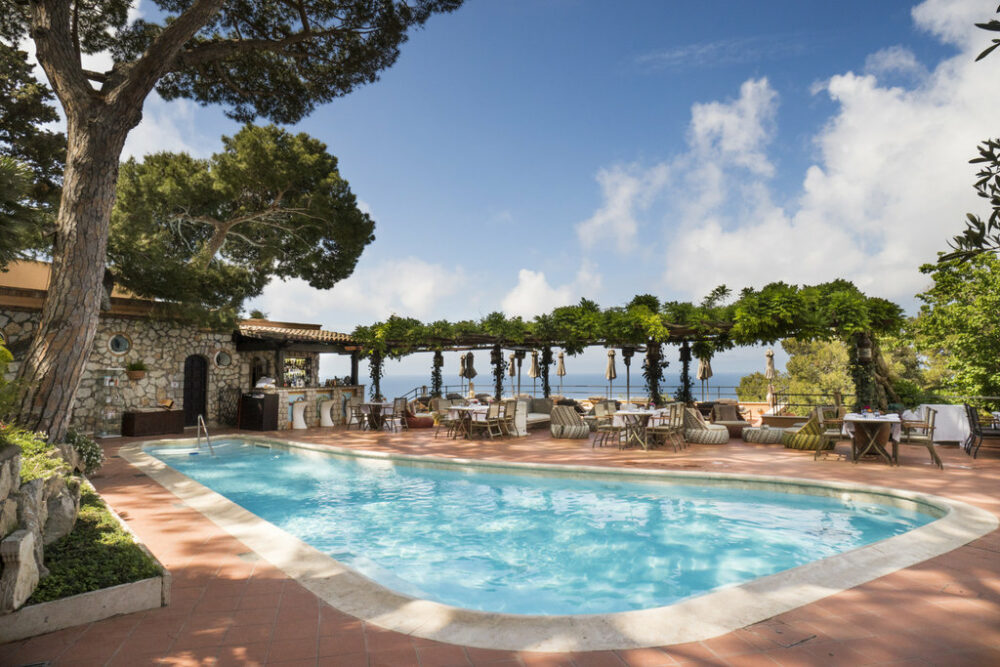 piscine extérieure d'un hôtel à Capri avec arbres et mer au loin
