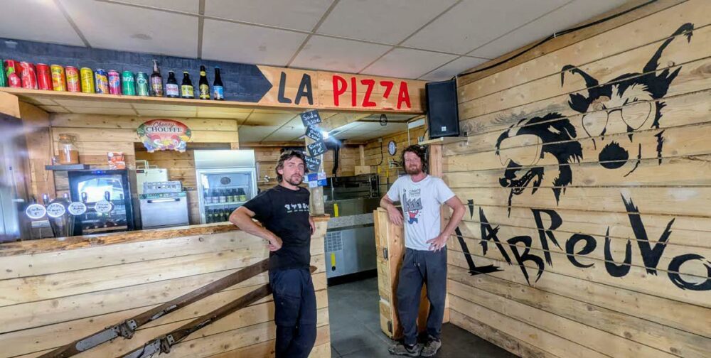 2 hommes posant dans une pizzeria décorée tout en bois