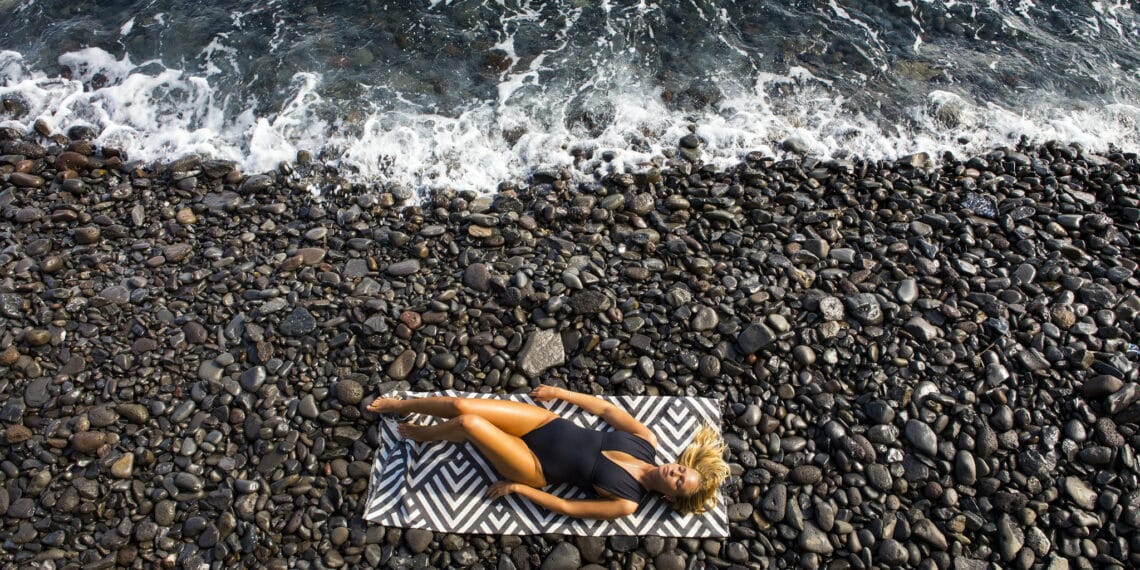 plage de galets femme allongée serviette