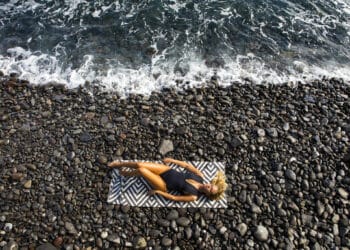 plage de galets femme allongée serviette