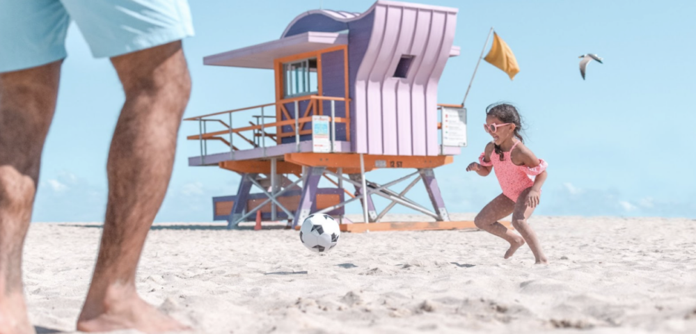 petite fille jouant au ballon avec son père sur la plage