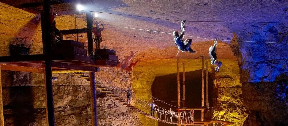 2 personnes qui descendent en tyrolienne dans une caverne