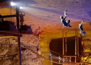 2 personnes qui descendent en tyrolienne dans une caverne