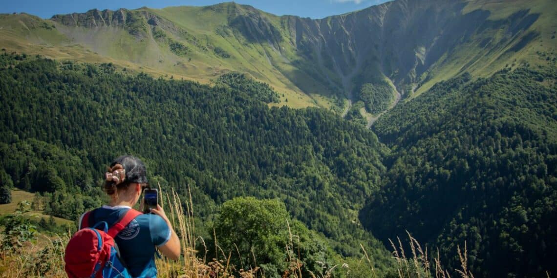 randonneuse de dos prenant une photo face aux montagnes
