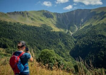 randonneuse de dos prenant une photo face aux montagnes