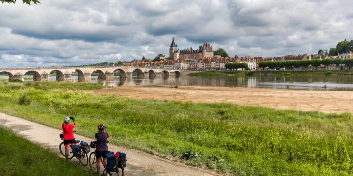 2 femmes cyclistes regardant avec des jumelles fleuve pont monument