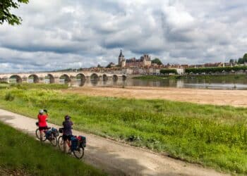 2 femmes cyclistes regardant avec des jumelles fleuve pont monument
