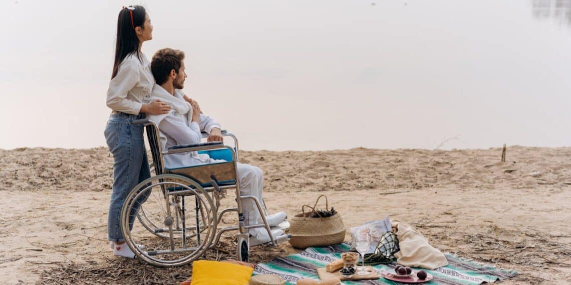 homme en fauteuil roulant femme sur la plage pique-niquant