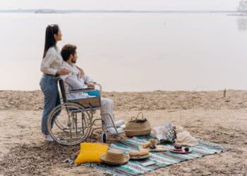 homme en fauteuil roulant femme sur la plage pique-niquant