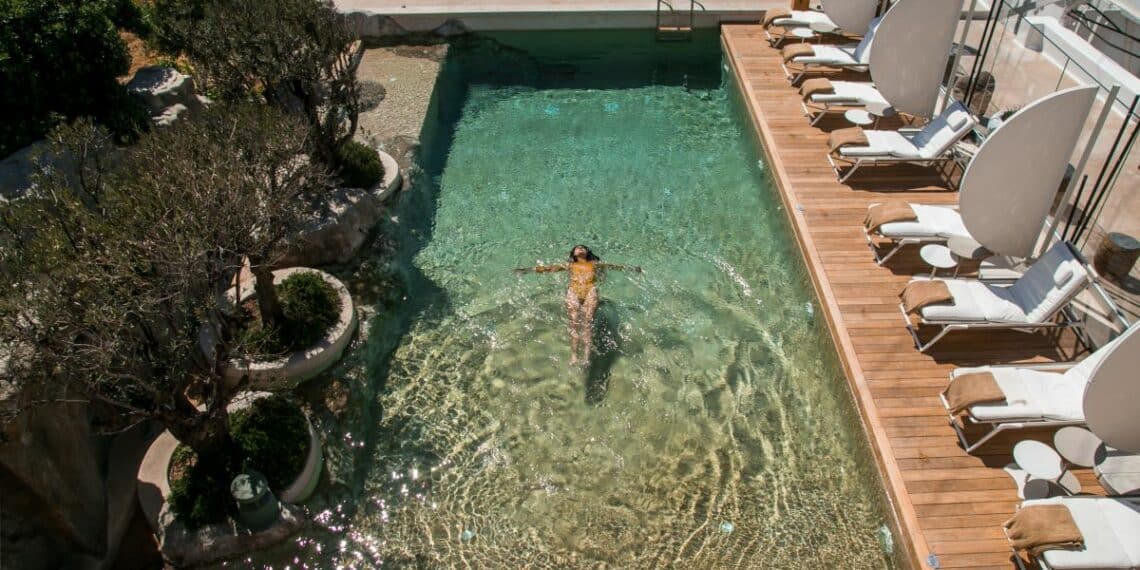 piscine extérieure femme se baignant sur le dos transats