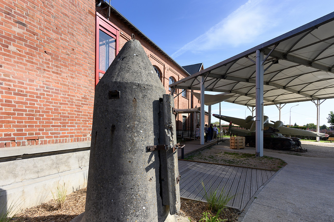 petit blockhaus individuel en béton devant un bâtiment en briques rouges